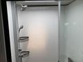 A modern shower unit featuring a showerhead and two soap baskets mounted on the wall with a clear shower door and sleek interior design
