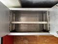 An empty metal storage compartment featuring two horizontal dividers and a smooth interior surface without contents
