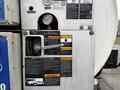 A close-up of the control panel on a 2013 International Workstar 7500 featuring gauges and warning labels related to water pressure and operation procedures
