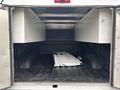 A 2020 Ford F-150 truck bed featuring a dark bed liner with two white storage compartments on either side and a silver metal object lying inside