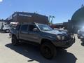 A gray 2010 Toyota Tacoma with a black grille and off-road tires parked in a lot