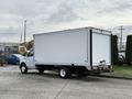A 2022 Ford E-450 box truck with a white cargo area parked with its rear door closed and visible wheels on a paved surface