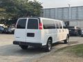A 2021 Chevrolet Express van in white with sliding side doors and a rear window panel parked in a lot