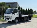 A white 2012 Hino 155 flatbed truck with a black cargo area and no cargo visible on the bed