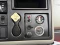 Dashboard controls of a 2014 International 7500 including a parking brake lever a pressure gauge and various buttons and indicators