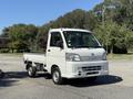 A white 2009 Daihatsu Hijet mini truck with a flatbed and compact design parked on a street