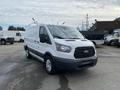 A white 2017 Ford Transit van with a gray lower body and a roof rack is parked with the front facing forward