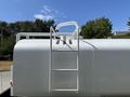 A white ladder is mounted on top of a large tank truck with smooth surfaces and a streamlined design