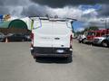 A white 2019 Ford Transit van viewed from the rear with a roof rack and a license plate visible