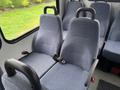 Two blue fabric seats with armrests and seatbelts inside a vehicle, designed for passenger transport