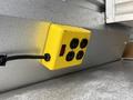 A yellow power outlet box with four sockets and a red switch mounted on a metal surface