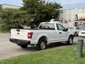 A white 2018 Ford F-150 pickup truck parked with a bed cover and chrome wheels