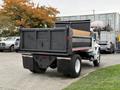 A 2006 International 4200 truck with a black dump bed and a wooden side panel parked in a lot