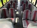 Interior of a 2011 Freightliner B2 bus showing rows of gray seats with red stripes and safety belts