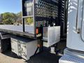 A 2020 Peterbilt 330 truck with a flatbed and visible aluminum storage compartments on the side and rear