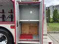 A 2002 GMC C7500 with an empty storage compartment featuring a wooden base and red rubber mat inside