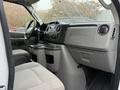 Interior view of a 2013 Ford Econoline showing the dashboard center console and two front seats in a light gray fabric