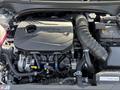 An engine compartment of a 2024 Kia Forte5 featuring a turbocharged engine with a sleek black cover and visible components like the alternator and air intake hose