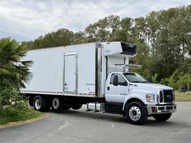 A white 2019 Ford F-750 truck with a large refrigerated box on the back parked at an angle