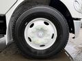 The image shows a close-up of a white wheel and tire from a 2005 Freightliner M2 106 featuring a five-bolt pattern and green wheel nuts