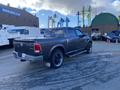 A 2017 RAM 1500 pickup truck in dark gray with custom wheels and a black stripe on the side parked at an industrial location