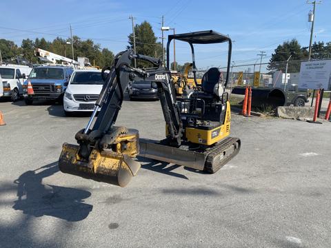 A yellow 2022 John Deere excavator with a black arm and bucket positioned in front of a construction site