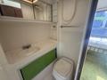 A compact bathroom area of a 1976 GMC Motorhome featuring a sink with a green cabinet underneath and a toilet with a padded seat