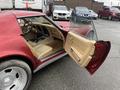 A red 1970 Chevrolet Corvette with an open door showcasing a tan interior and steering wheel