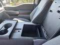 A 2023 Ford F-350 SD features a black center console with a cup holder and storage compartment, upholstered in gray fabric