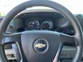 Steering wheel of a 2013 Chevrolet Silverado 1500 with a black leather cover featuring the Chevrolet logo and instrument panel gauges visible behind the wheel
