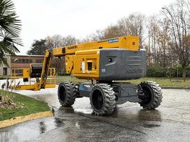 A yellow Haulotte HA61 LE PRO aerial work platform with tracks and an extended boom positioned for use