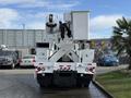 A 2011 International 4300 bucket truck with a raised boom and attached bucket at the rear, featuring a white exterior and multiple lights mounted on the body
