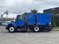 A blue 2013 International DuraStar 4300 street sweeper with a large vacuum compartment and a front broom attachment