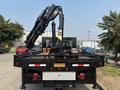 A 2009 Ford F-450 Super Duty flatbed truck with a crane attachment extending from the rear of the truck