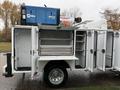 A 2024 RAM 5500 truck with an open utility bed showing multiple storage compartments and equipped with a generator unit on top