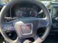 Close-up view of the steering wheel of a 2014 GMC Sierra 1500 featuring the GMC logo and vehicle controls on the left side