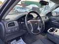 Interior view of a 2011 Chevrolet Avalanche featuring a steering wheel dashboard controls and center console with cup holders