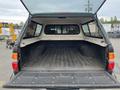 The open bed of a 2004 Toyota Tacoma showing a lined cargo area with a cap and a rear view of the truck's tail lights