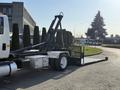 A 2017 International 4300 truck with a flatbed and hydraulic lift system in a parked position