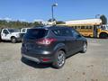 A 2016 Ford Escape in dark gray color with chrome wheels parked in a lot, showcasing its rear and side features
