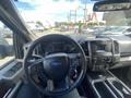 Interior view of a 2015 Ford F-150 featuring a steering wheel dashboard and center console with controls and gauges