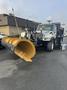 A 2007 International 7300 truck equipped with a large yellow snow plow attached to the front