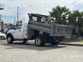 A 2016 RAM 5500 dump truck with its bed raised is parked with construction equipment visible in the truck bed