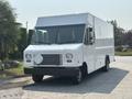 A white 2018 Ford Econoline van with a boxy design featuring large front windows and a flat hood parked on a driveway