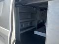 A 2019 Ford Transit 350 van interior showing metal shelving units along the side and a spacious cargo area with a flat floor