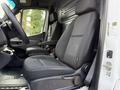 A 2021 Mercedes-Benz Sprinter van interior featuring two black front seats with armrests and a dashboard with various controls and compartments