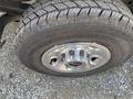 Close-up of a chrome wheel rim and tire of a 2023 GMC Savana showcasing a rugged tread pattern and shiny hubcap