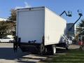 A white 2012 Freightliner M2 106 box truck with a closed cargo area and a clear rear view, positioned on flat ground