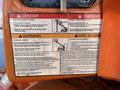 A warning label on a JLG E400AJFN with danger notices about electrocution and crushing hazards including safety instructions and inspection requirements