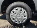 A close-up of a silver wheel rim with a unique design mounted on a black tire from a 2016 Ford Transit 150